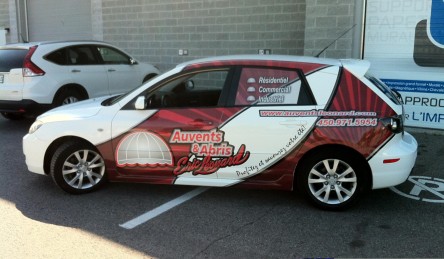White car with red and black lettering for Auvents & Abris Eric Leonard, showing contact info and services.